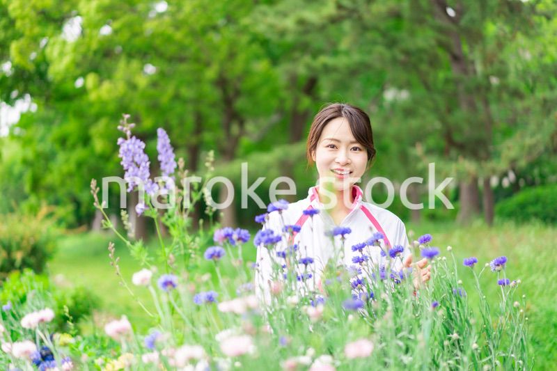 庭で花の世話をする若い女性