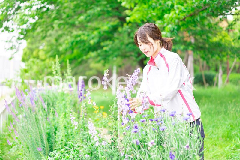 庭で花の世話をする若い女性