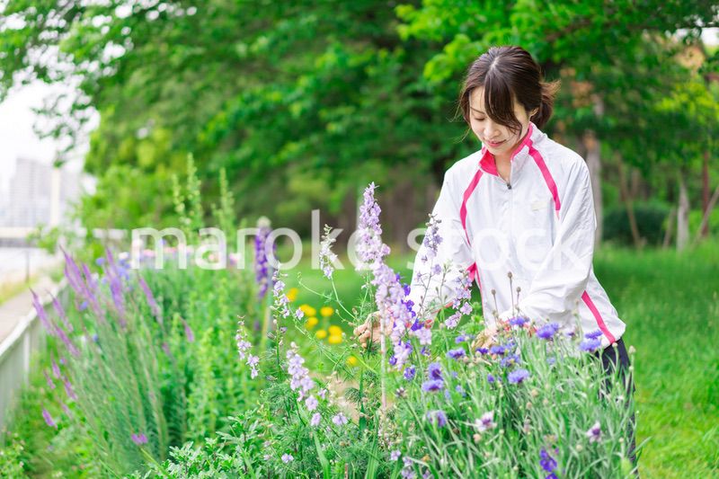 庭で花の世話をする若い女性