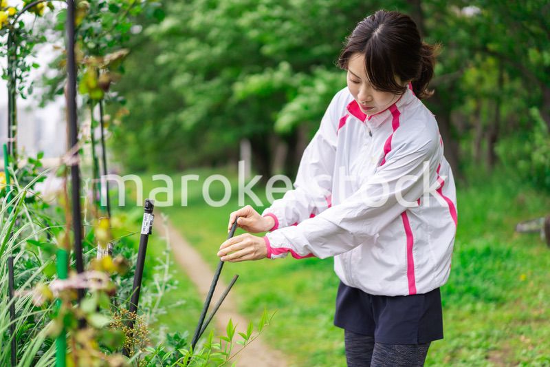 庭で花の世話をする若い女性