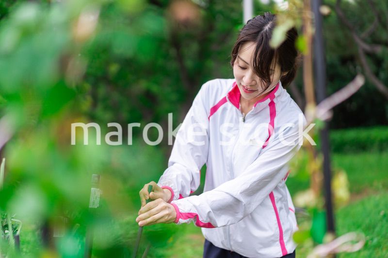 庭で花の世話をする若い女性