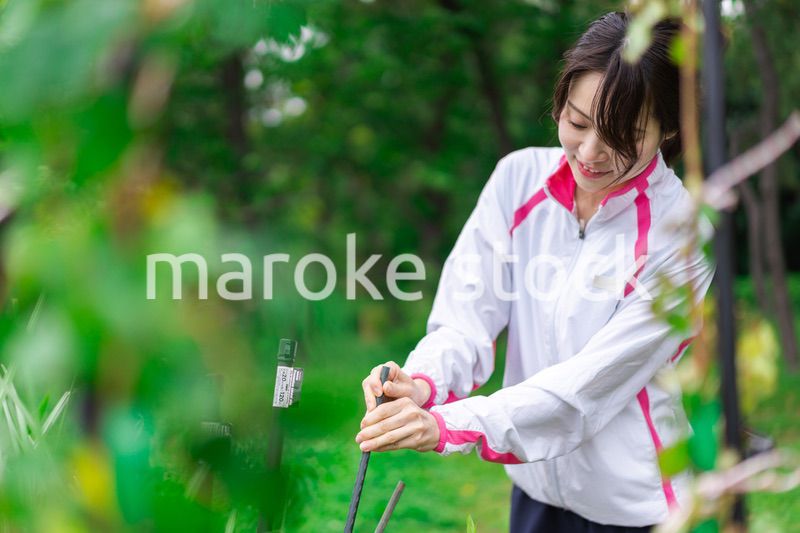 庭で花の世話をする若い女性