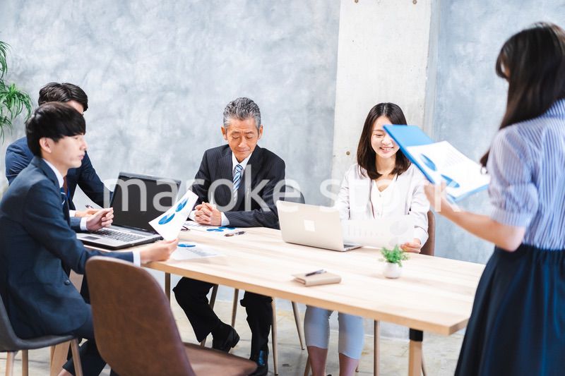 商品企画のプレゼンテーションを聞くビジネスパーソン