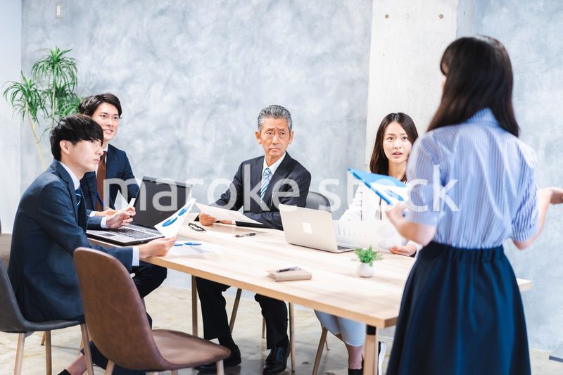 商品企画のプレゼンテーションを聞くビジネスパーソン