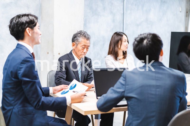 商品企画のプレゼンテーションを聞くビジネスパーソン