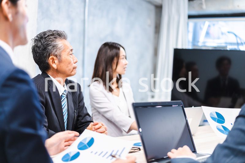 商品企画のプレゼンテーションを聞くビジネスパーソン