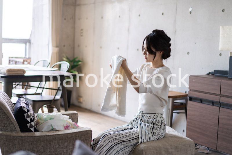 家で洗濯物をたたむ若い女性