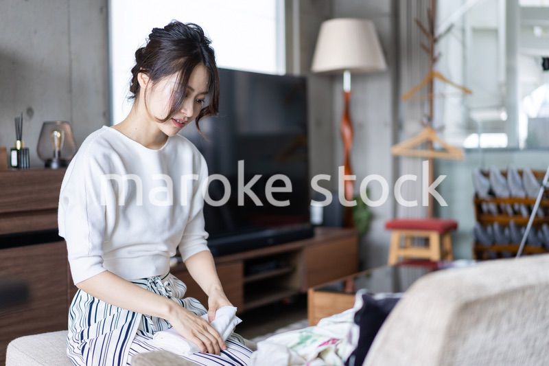 家で洗濯物をたたむ若い女性