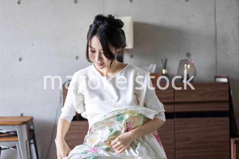 家で洗濯物をたたむ若い女性