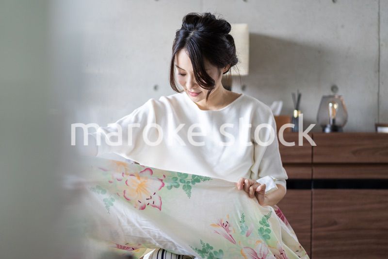 家で洗濯物をたたむ若い女性