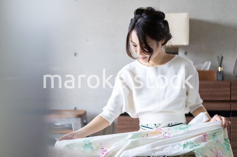 家で洗濯物をたたむ若い女性