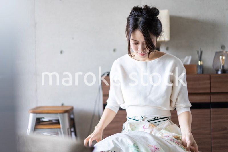 家で洗濯物をたたむ若い女性