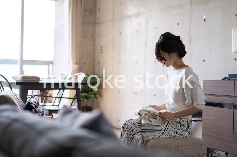 家で洗濯物をたたむ若い女性