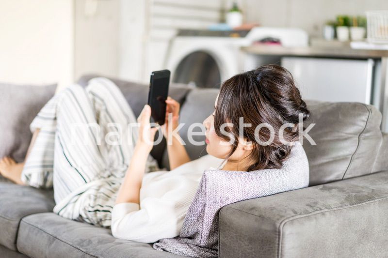 部屋でスマホを使う若い女性