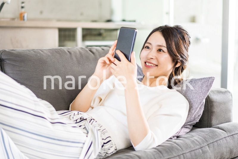 部屋でスマホを使う若い女性