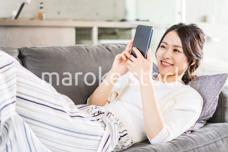 部屋でスマホを使う若い女性