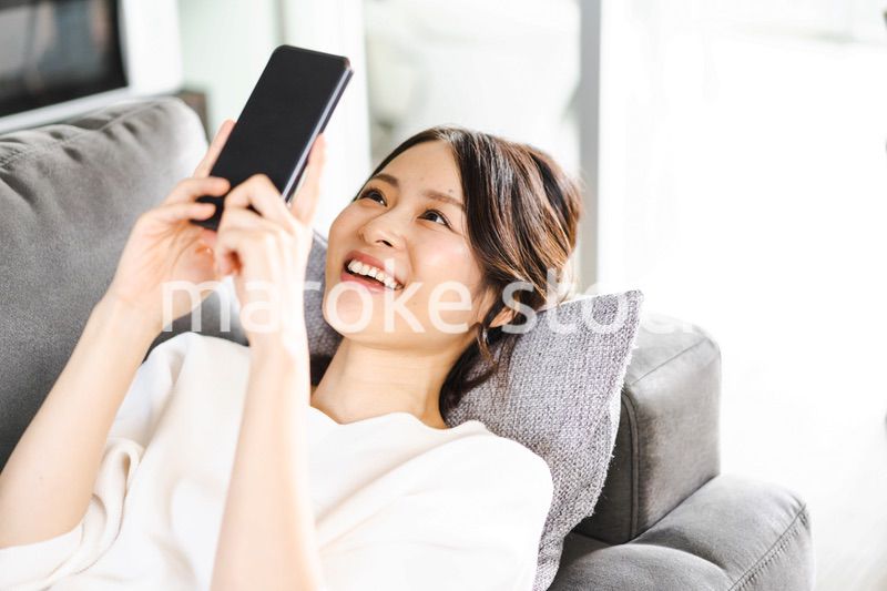 部屋でスマホを使う若い女性