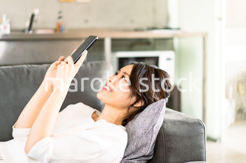 部屋でスマホを使う若い女性
