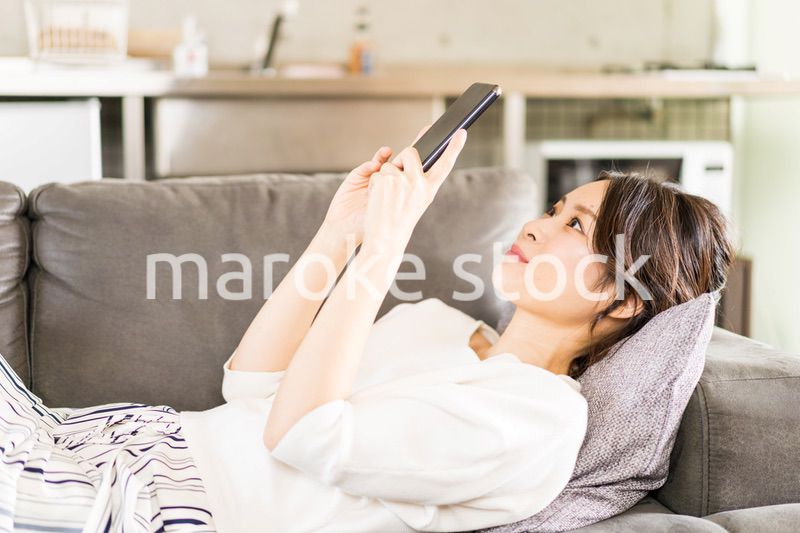 部屋でスマホを使う若い女性