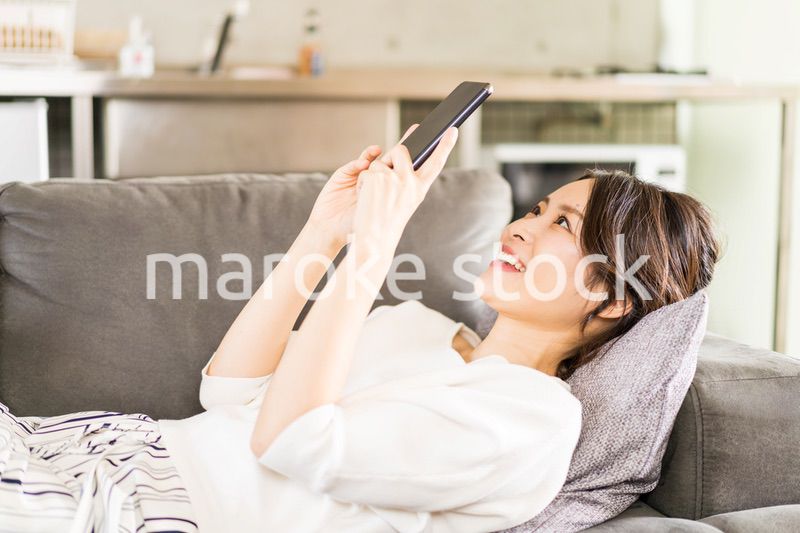 部屋でスマホを使う若い女性