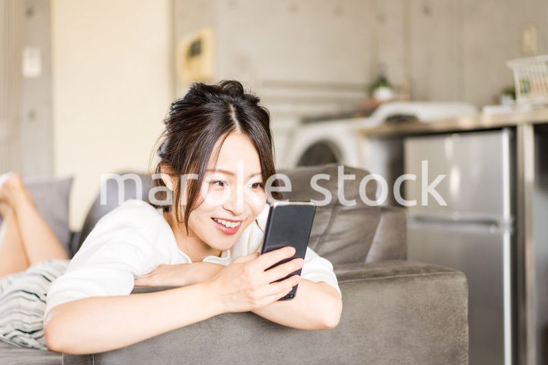 部屋でスマホを使う若い女性