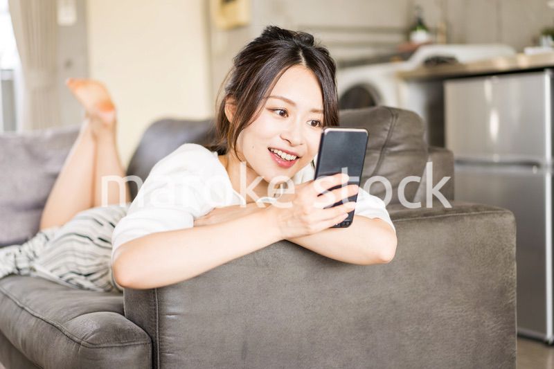 部屋でスマホを使う若い女性