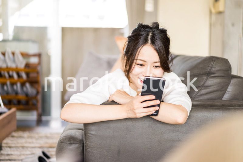 部屋でスマホを使う若い女性