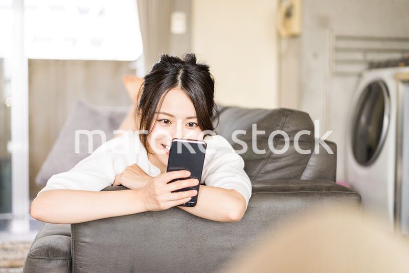 部屋でスマホを使う若い女性