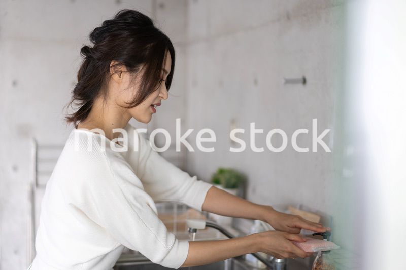 家で洗い物をする若い女性