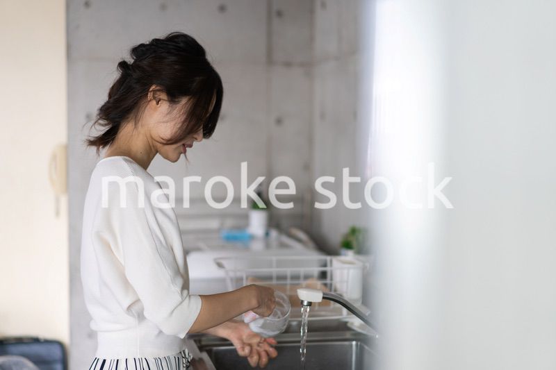 家で洗い物をする若い女性