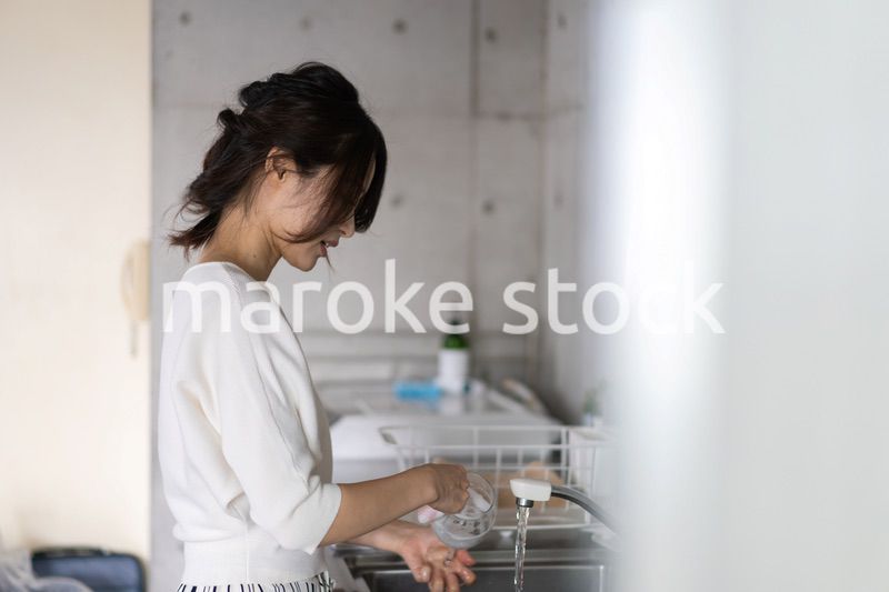 家で洗い物をする若い女性