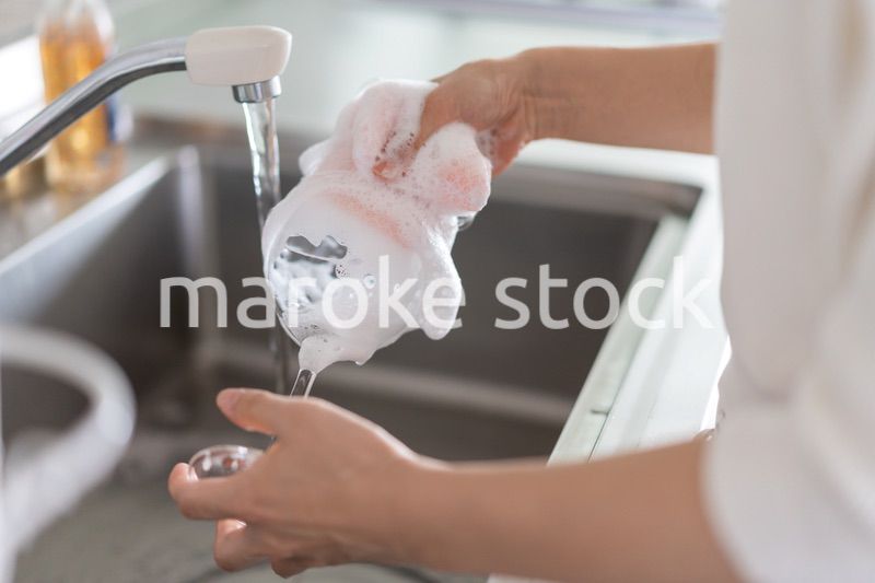家で洗い物をする若い女性