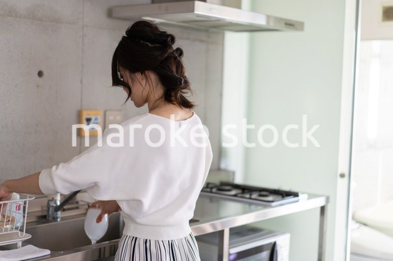 家で洗い物をする若い女性