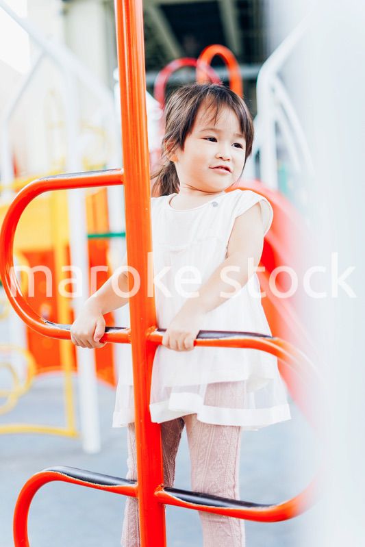公園の遊具で遊ぶ小さな女の子