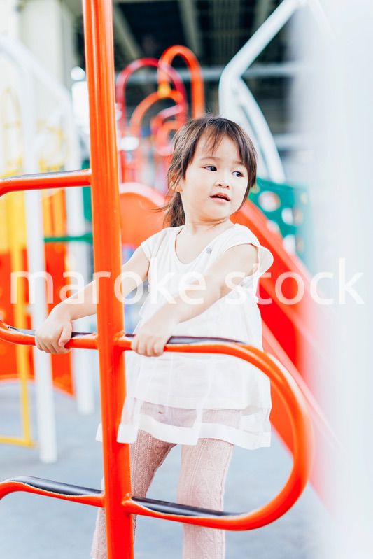 公園の遊具で遊ぶ小さな女の子