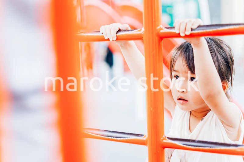 公園の遊具で遊ぶ小さな女の子