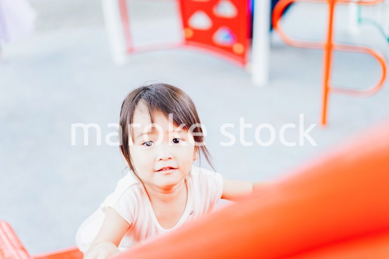 公園の遊具で遊ぶ小さな女の子