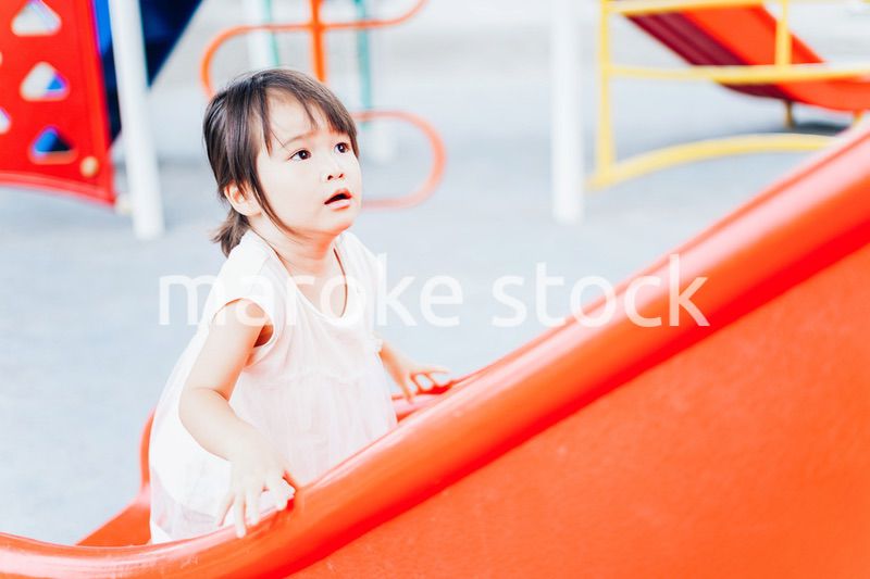 公園の遊具で遊ぶ小さな女の子