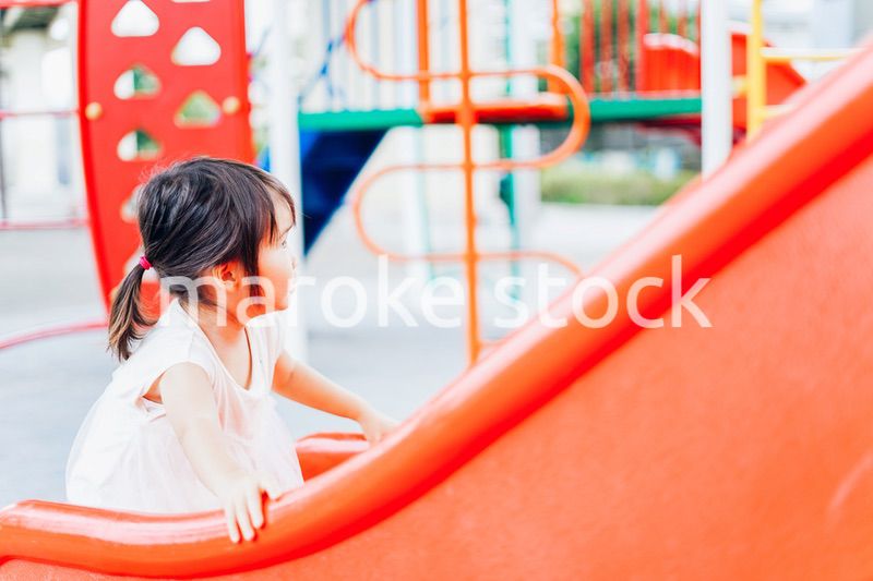 公園の遊具で遊ぶ小さな女の子