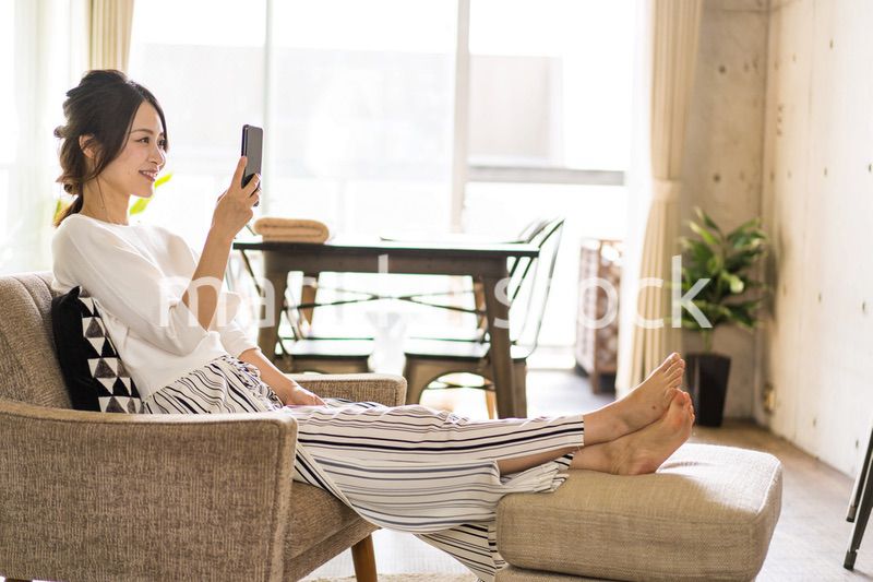 部屋でスマホを使う若い女性