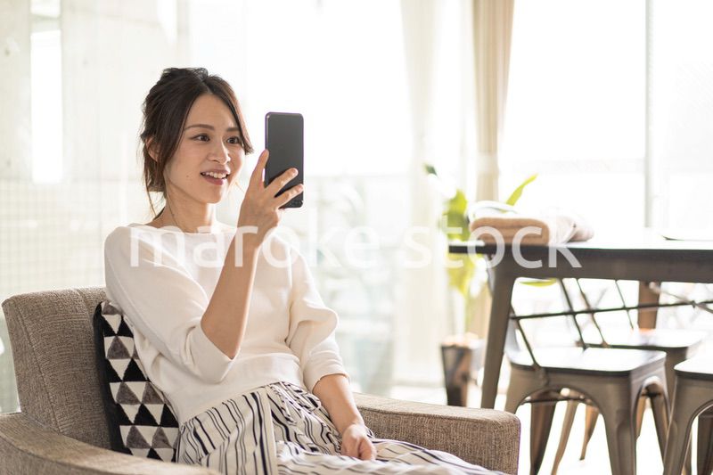 部屋でスマホを使う若い女性
