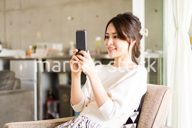 部屋でスマホを使う若い女性