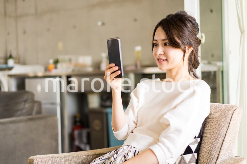 部屋でスマホを使う若い女性