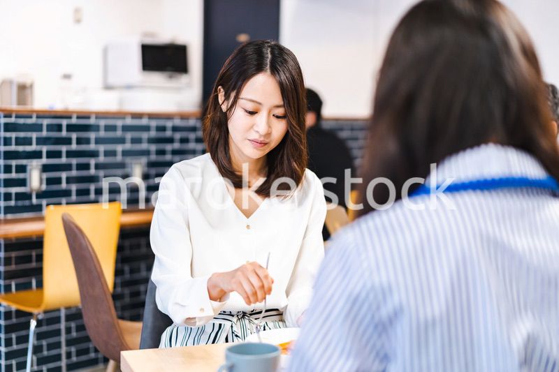 明るい雰囲気の社員食堂でランチを取るオフィスワーカー