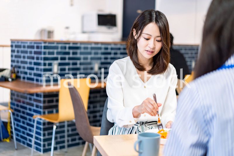 明るい雰囲気の社員食堂でランチを取るオフィスワーカー