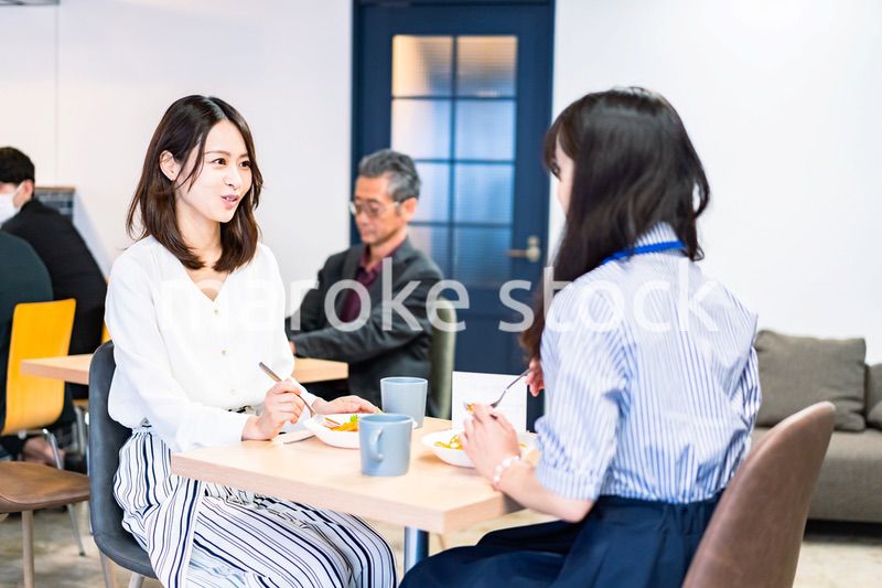 明るい雰囲気の社員食堂でランチを取るオフィスワーカー