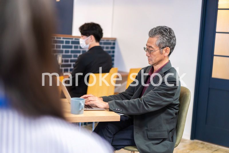 カフェで仕事をする中年男性
