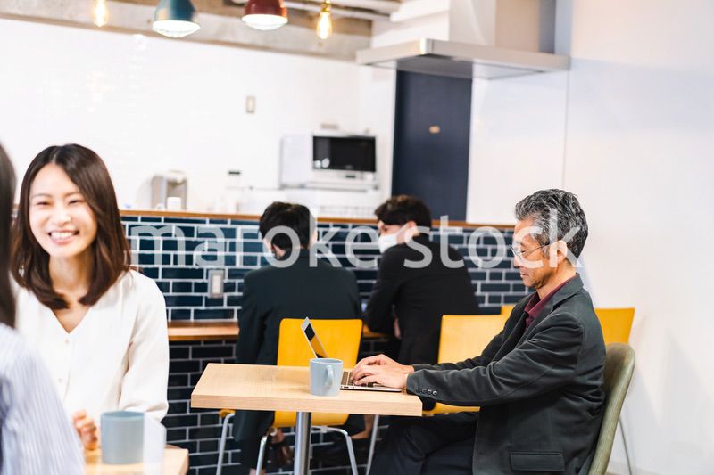 明るい雰囲気の社員食堂でランチを取るオフィスワーカー