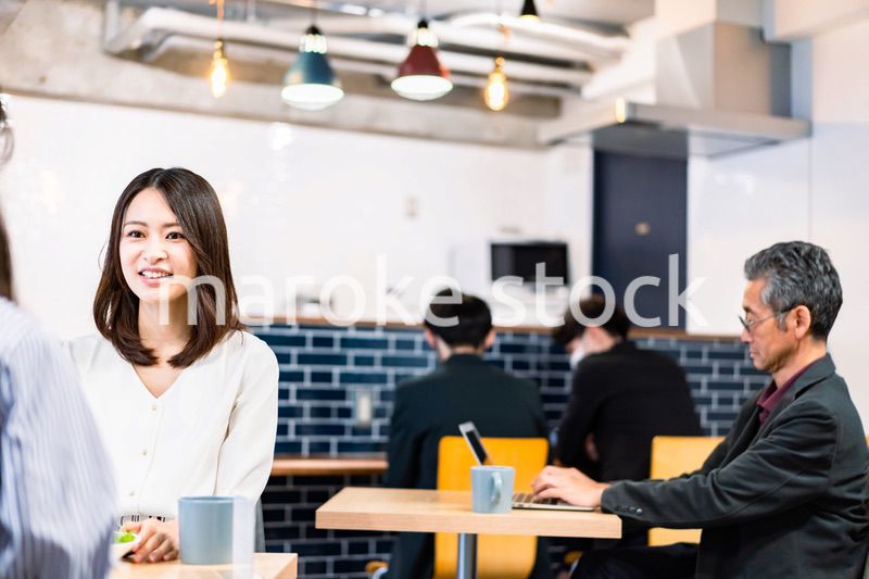 明るい雰囲気の社員食堂でランチを取るオフィスワーカー