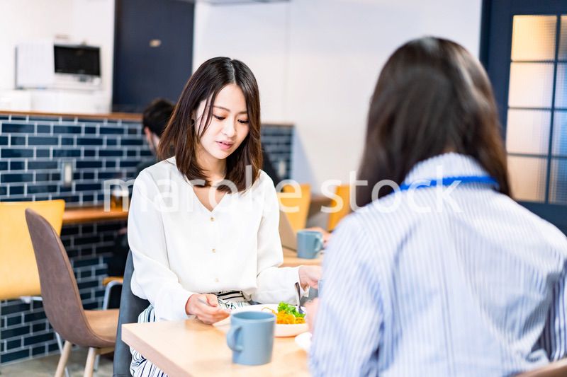 明るい雰囲気の社員食堂でランチを取るオフィスワーカー